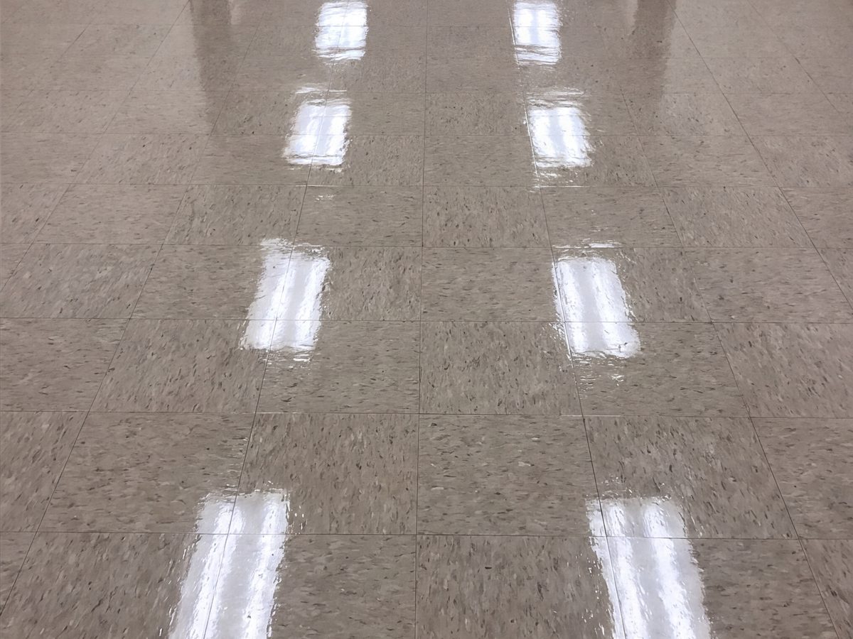 The same corridor after stripping and waxing: the light fixtures reflect in the floor